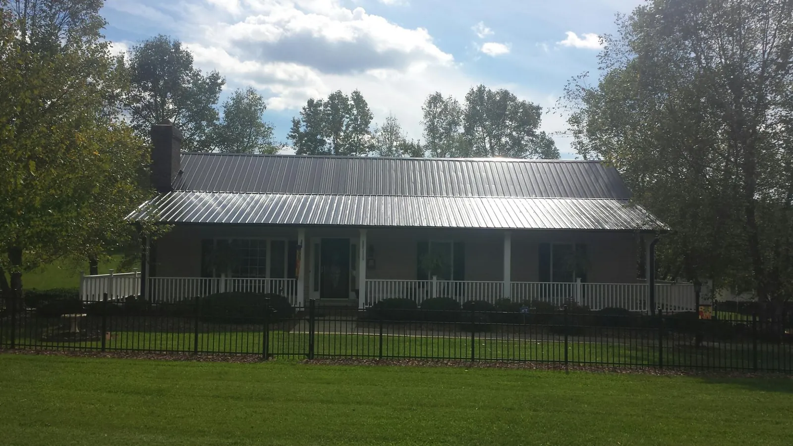 Gray metal roof on a brick ranch with a full width front porch — Gutter Guard Installation work by our crew in Converse