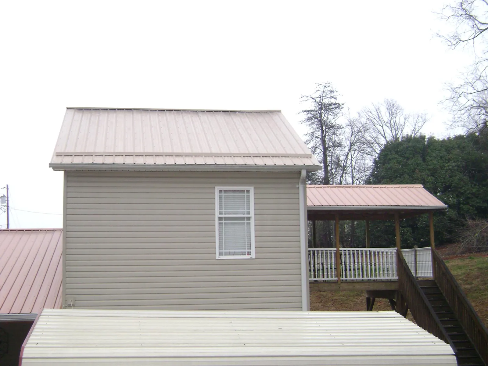 Tan metal roofs on a two story addition and attached porch, from a Roof Replacement job in Converse
