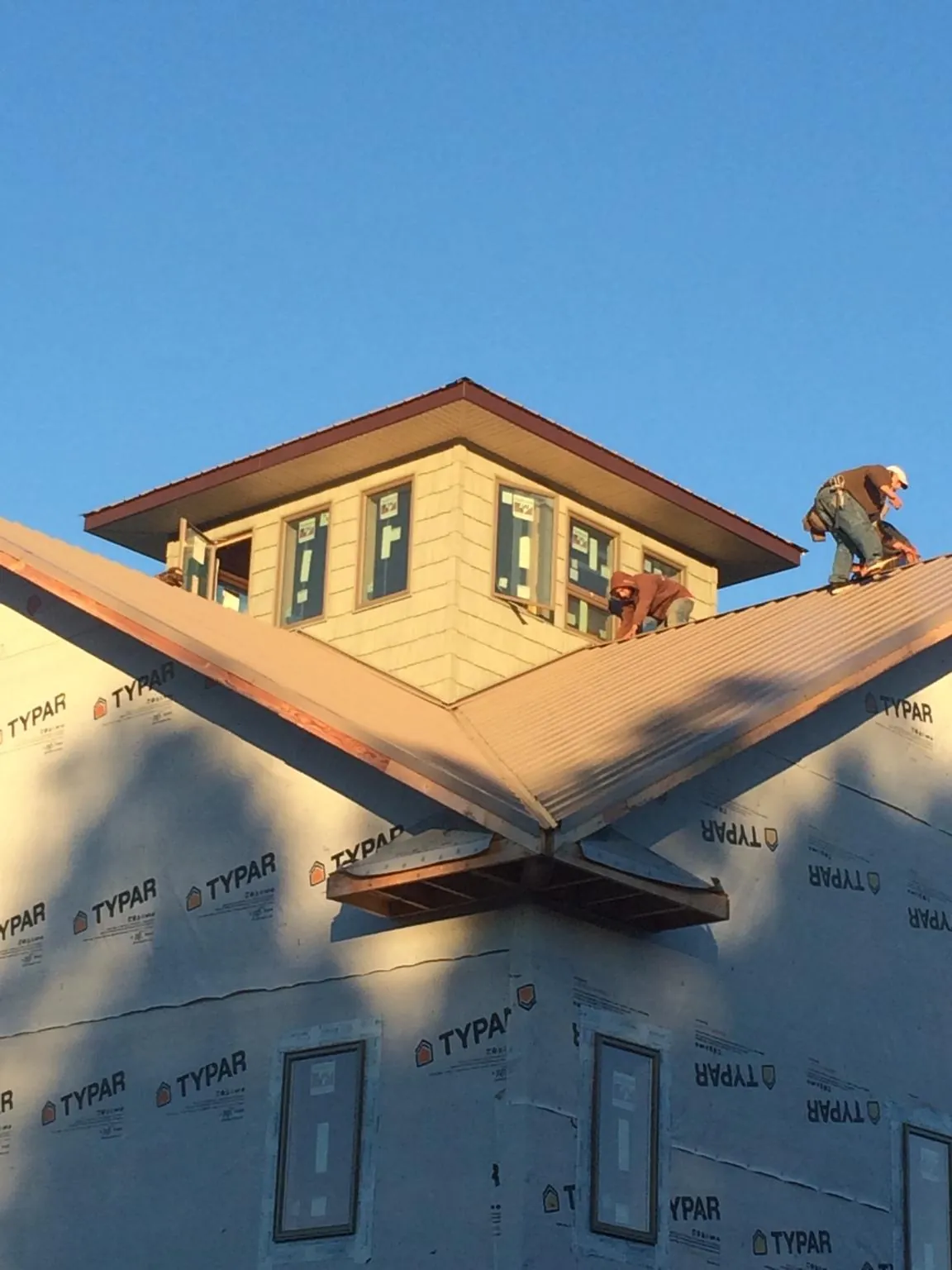 Roofers working around a rooftop cupola on a new metal roof at sunset — Roof Waterproofing in Converse by Roofing Brothers